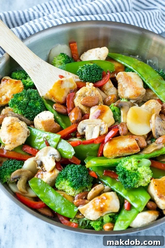 Chicken almond ding with sauteed chicken breast, mixed vegetables and almonds in a skillet.