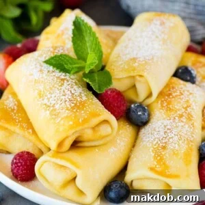 Cheese blintzes garnished with powdered sugar and berries.