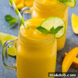 Mango smoothie in a mug topped with a slice of lime and mint sprig.