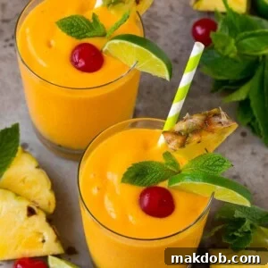 Tropical smoothies garnished with mint, limes and pineapple.