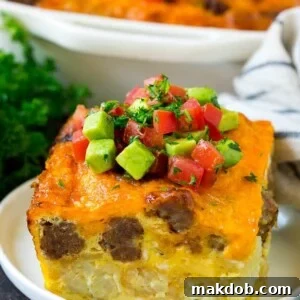 A slice of sausage egg casserole with a garnish of fresh tomatoes.
