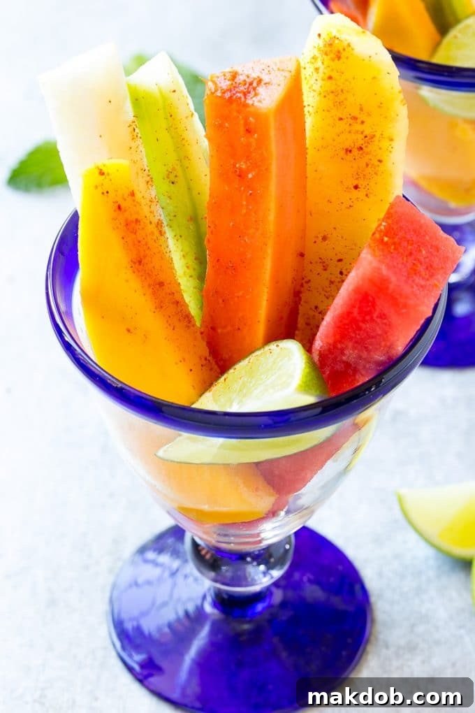 Fruit cups filled with watermelon, cucumber, papaya and mango, ready for chili lime seasoning.