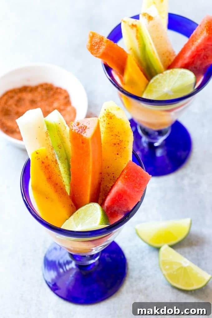 Spears of watermelon, cucumber, jicama, mango and pineapple in glasses, ready to be seasoned.