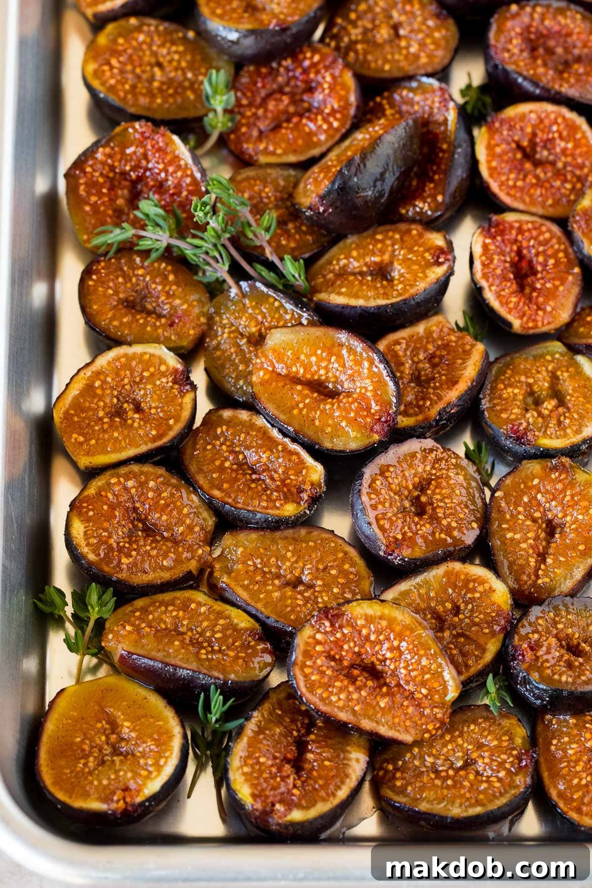 Luscious Roasted Figs 2 Roasted figs on a sheet pan, garnished with sprigs of thyme, showcasing their caramelized perfection.