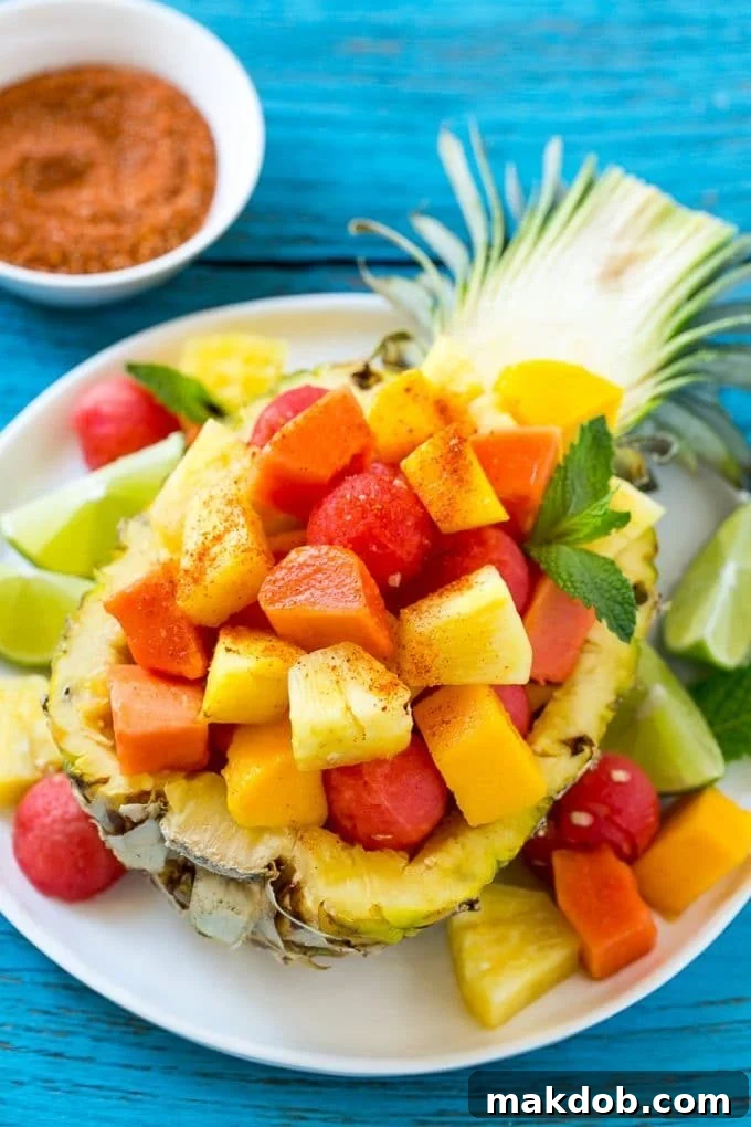 Colorful Mexican fruit salad featuring pineapple, mango, papaya, and watermelon chunks, ready for seasoning.