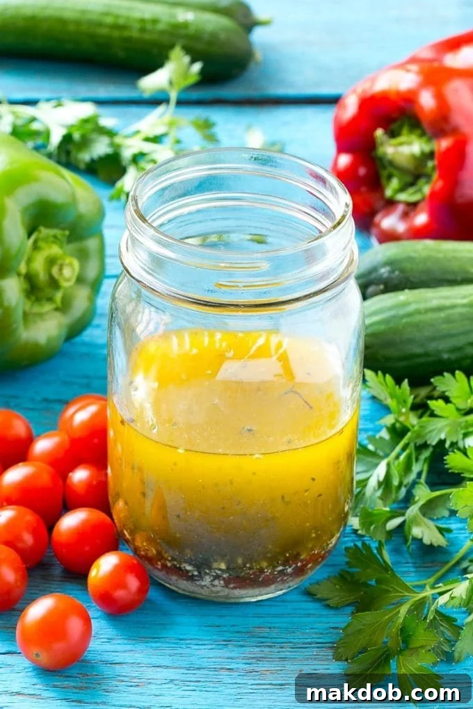 A glass jar filled with vibrant homemade Italian dressing, showing herbs and oil separated, ready to be shaken.