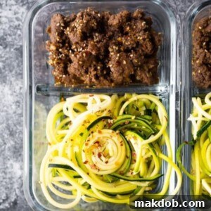 A container filled with savory sesame ginger beef zucchini noodles.
