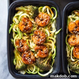 Meal prep containers with shrimp zoodles and vibrant broccoli.