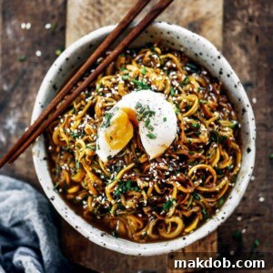 An appetizing Asian zucchini noodle bowl, topped with a perfectly soft-boiled egg.