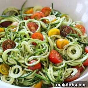 A vibrant bowl of raw zucchini noodles, fresh tomatoes, and homemade pesto.