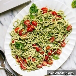 A platter of fresh zucchini pesto zoodles garnished with cherry tomatoes.