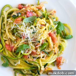 A dish of zucchini noodles pasta with garlic, fresh tomatoes, and basil.