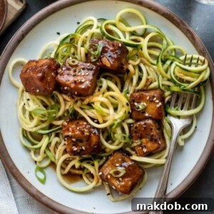 A plate showcasing sweet and spicy crispy tofu served over zucchini noodles.