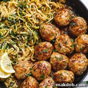 A picture of savory garlic butter meatballs served alongside lemon zucchini noodles.