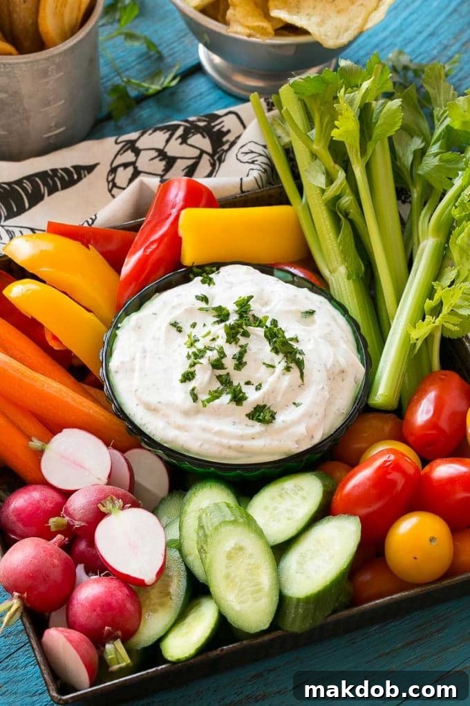 Homemade Ranch Dip Recipe | Homemade Ranch Powder | Homemade Ranch Dressing | Best Ranch Dip #ranch #dip #appetizer #snack #dinneratthezoo A beautifully presented bowl of creamy homemade ranch dip, garnished with a sprinkle of fresh green herbs, and artfully surrounded by an assortment of colorful, fresh-cut vegetables like crisp carrots, vibrant bell peppers, crunchy celery, and refreshing cucumber slices, all ready for dipping.