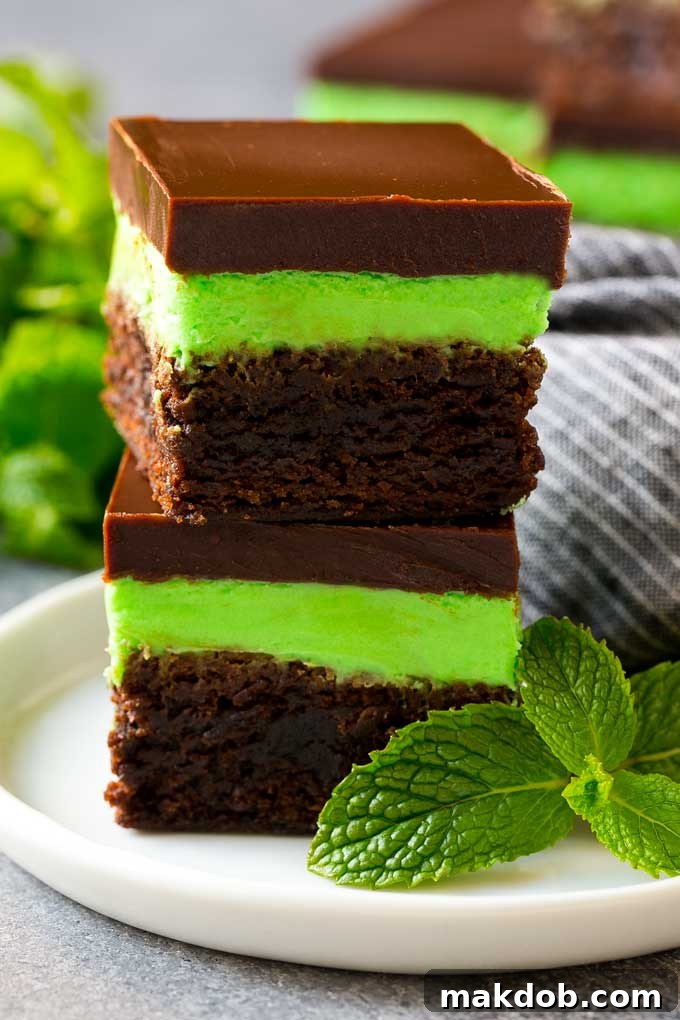 Mint Brownies Recipe | Layered Brownies | Frosted Brownies #brownies #chocolate #frosting #mint #dessert #dinneratthezoo A stack of mint brownies topped with mint and chocolate frostings.
