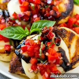 Grilled bruschetta chicken, featuring melted mozzarella, fresh tomato basil bruschetta, and a drizzle of balsamic glaze.