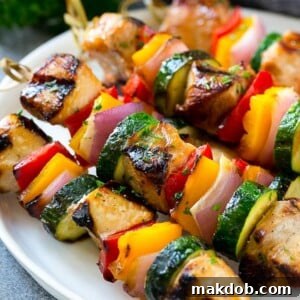 A tempting plate of grilled chicken kabobs, artfully made with marinated chicken and a vibrant assortment of colorful vegetables.