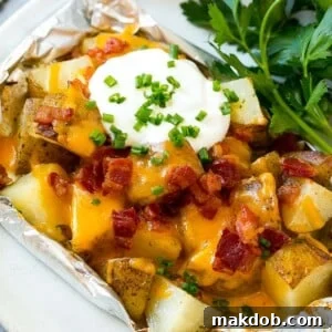 Perfectly grilled potatoes cooked in foil, served on a plate and garnished with fresh herbs.