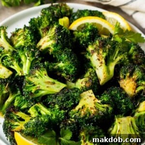 Perfectly grilled broccoli florets, topped with fresh parsley and garnished with bright lemon wedges.