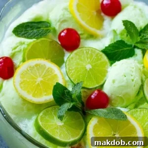 Vibrant lime sherbet punch, garnished with an assortment of fresh cherries, lemons, limes, and mint leaves.