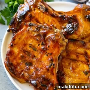 Bone-in BBQ pork chops, perfectly grilled and generously topped with a rich barbecue sauce.