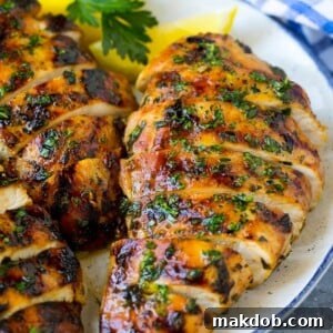 Succulent sliced grilled chicken breast, elegantly garnished with fresh herbs and a wedge of lemon.