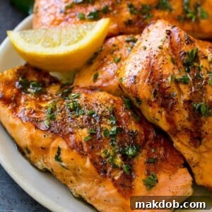 Marinated salmon fillets, grilled to perfection and adorned with fresh lemon, garlic, and herbs.