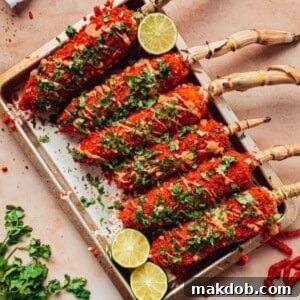 A vibrant tray laden with multiple Flaming Hot Cheetos Elotes, showcasing their fiery red coating and tantalizing appearance.