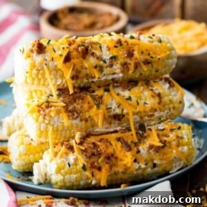 A delectable stack of cheddar bacon corn on the cob, generously coated with melted cheddar cheese and crispy bacon bits. The vibrant yellow of the corn contrasts beautifully with the rich red-orange of the cheese and the darker bacon, promising a savory, cheesy, and irresistible flavor combination that's perfect for comfort food lovers.