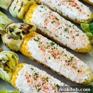Authentic Mexican street corn (Elote), featuring grilled corn on the cob lavishly coated in a creamy white mixture. The corn is generously sprinkled with cotija cheese, vibrant green cilantro, and a dusting of reddish chili powder, highlighting a perfect balance of savory, tangy, and spicy flavors for an iconic street food experience.
