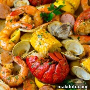 An abundant sheet pan seafood boil overflowing with fresh, vibrant ingredients including succulent shrimp, luxurious lobster tails, savory sausage, sweet corn on the cob, and tender potatoes. This colorful and rich display is a feast for the eyes, promising a celebratory and deeply flavorful dining experience that's perfect for sharing.