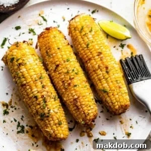 An appetizing image displaying three perfectly cooked ears of air fryer corn on the cob arranged neatly on a plate, ready to be enjoyed.