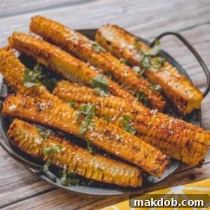 A tempting platter of several golden-brown corn ribs, artfully arranged and garnished with fresh herbs and grated vegan parmesan. The distinctive curled shape of the corn ribs suggests a delightful crispiness, inviting viewers to savor this unique and plant-based twist on a classic.