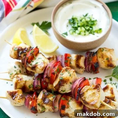 A delicious Greek chicken kabobs dish with garlic and herb marinated chicken and colorful vegetables, skewered and grilled, served with a creamy cucumber yogurt dip.