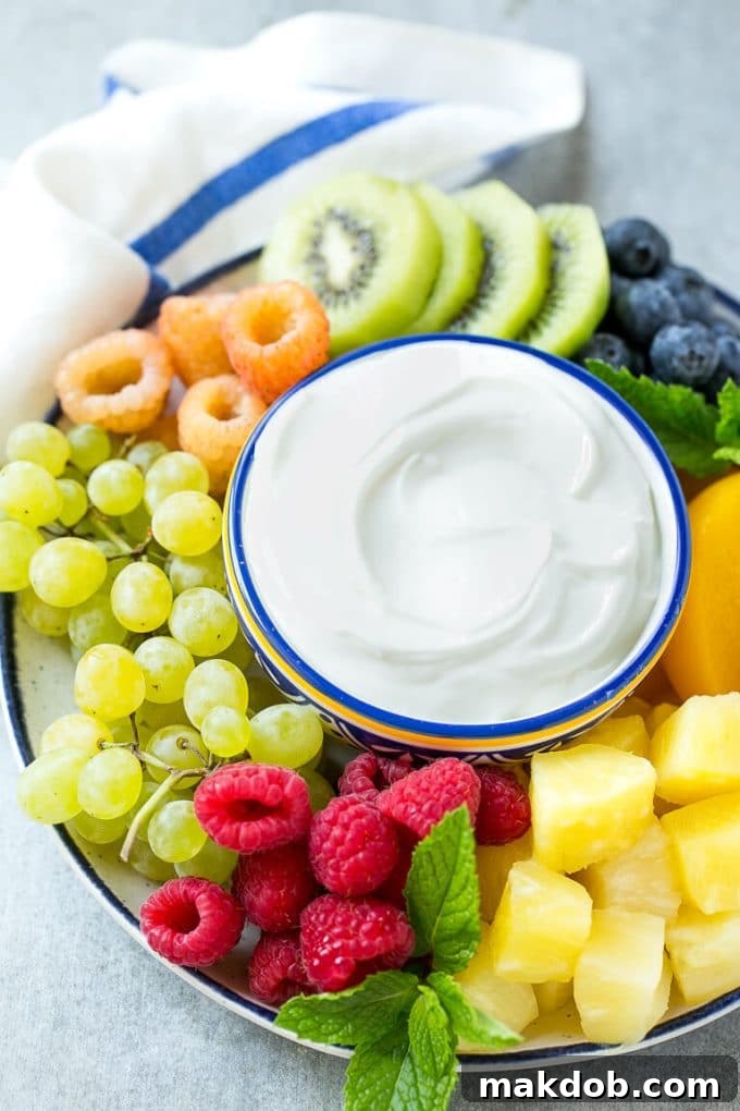 A vibrant bowl of cream cheese fruit dip surrounded by a colorful array of fresh fruit, highlighting its inviting nature.