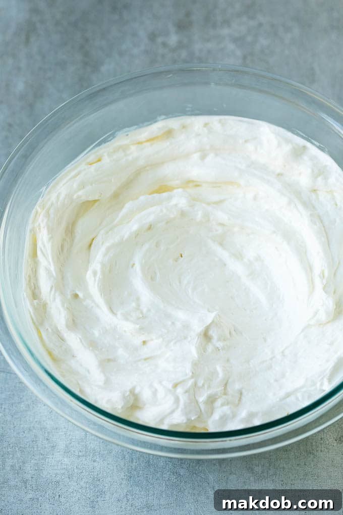 Cream cheese, marshmallow cream and whipped topping in a mixing bowl, ready to be combined into a delicious fruit dip.