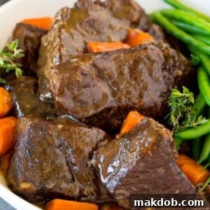 A hearty bowl of Instant Pot short ribs, swimming in a rich sauce and accompanied by tender carrots and crisp green beans.