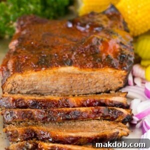 Perfectly cooked Instant Pot brisket on a serving tray, garnished with fresh red onions and accompanied by corn on the cob.