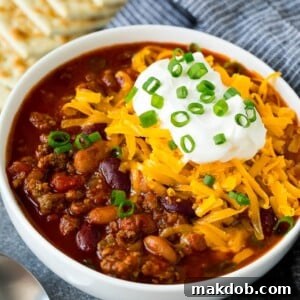 A hearty bowl of Instant Pot chili, generously topped with cool sour cream, shredded cheese, and vibrant green onions.