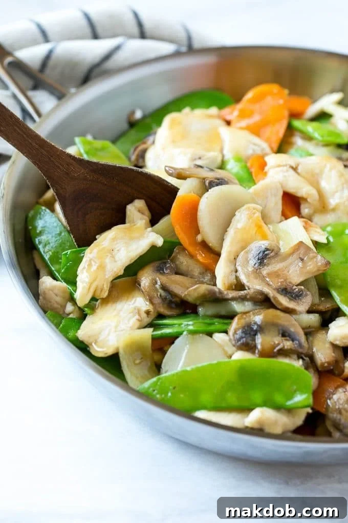 A skillet of moo goo gai pan with a serving spoon in it. Ready to serve this healthy and delicious chicken and mushroom stir fry.