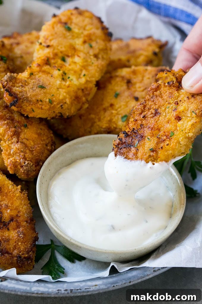 Baked Fried Chicken A chicken finger being dipped into ranch dressing.