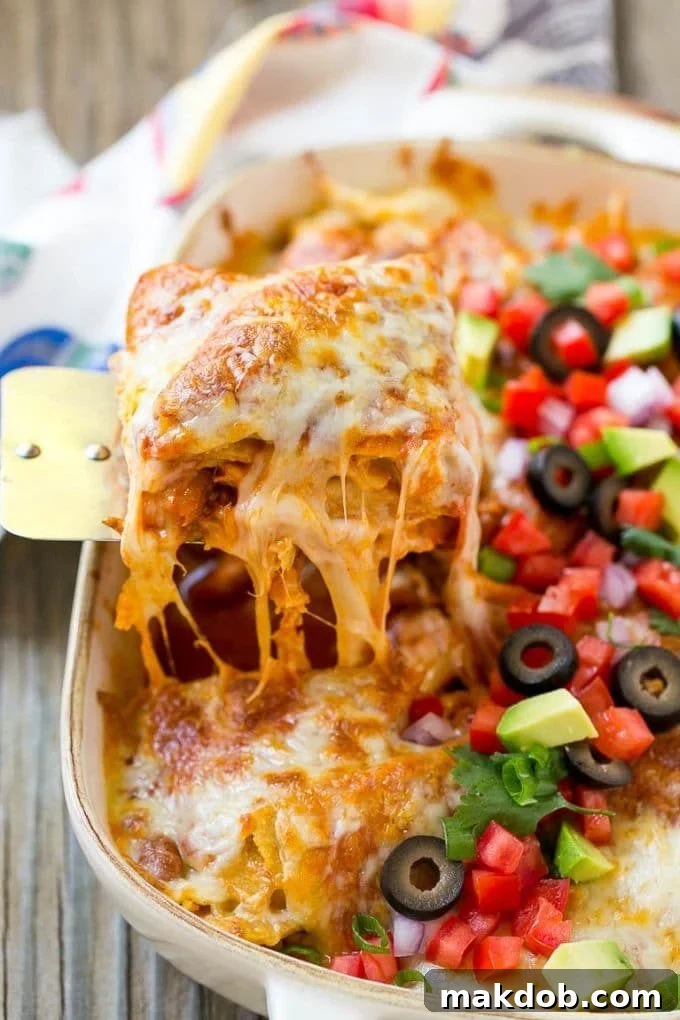A spatula serving up a portion of cheesy chicken enchilada casserole.