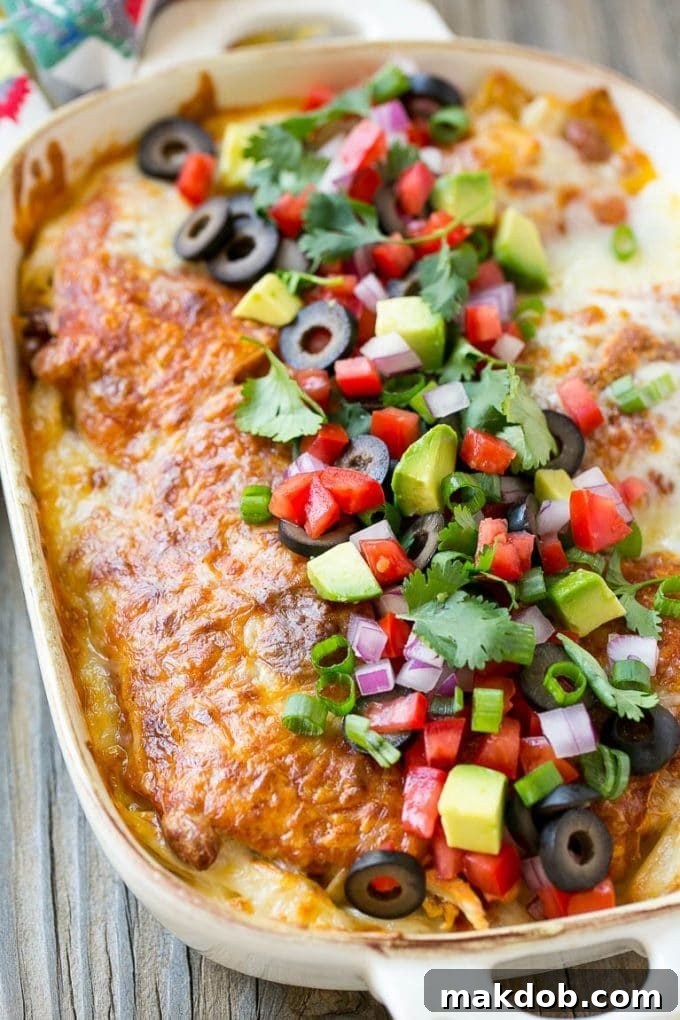 Chicken enchilada casserole topped with avocado, tomatoes and olives.