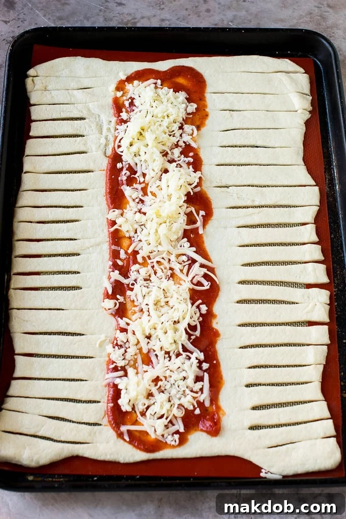 A sheet of pizza dough topped with tomato sauce and mozzarella cheese.