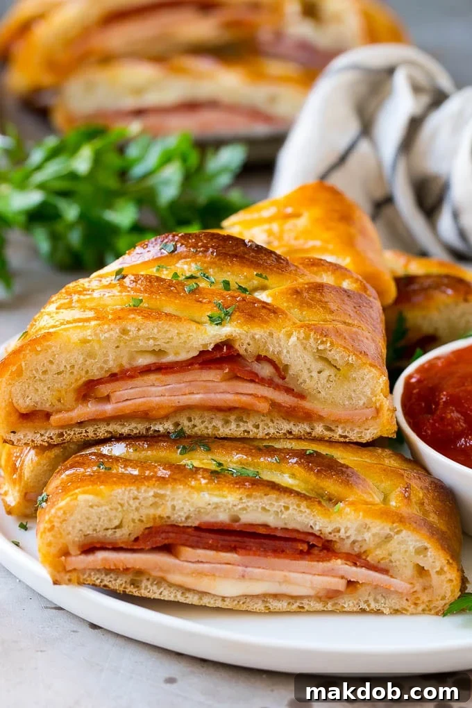 Italian stromboli layered with meats and cheese and served with a side of tomato sauce.