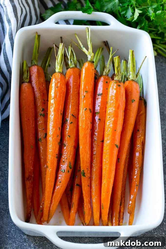 A baking dish of honey roasted carrots topped with parsley.