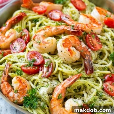 Delicious Shrimp Pesto Pasta ready to eat, topped with tomatoes and cheese.