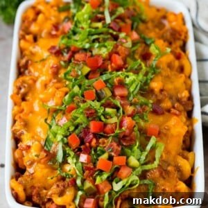 A hearty cheeseburger casserole, brimming with seasoned ground beef and macaroni, generously topped with melted cheese, crispy bacon, and fresh tomatoes.