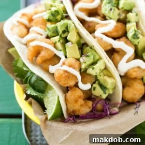 A vibrant plate of fried shrimp tacos, generously filled with crispy shrimp, a refreshing cilantro lime cabbage slaw, and a creamy avocado relish.